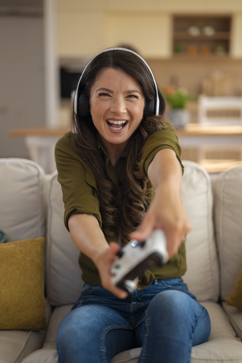 Woman gaming with headphones, smiling enthusiastically.